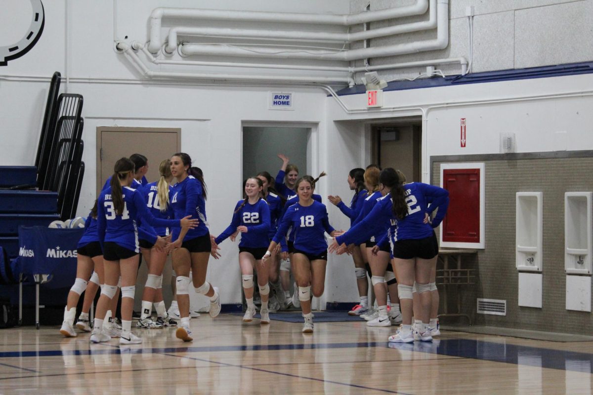 Jv high fiving varsity as they enter the court.